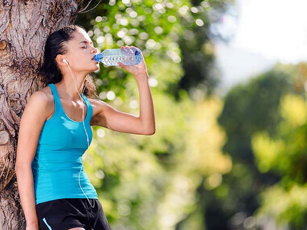 mulher tomando água durante exercício